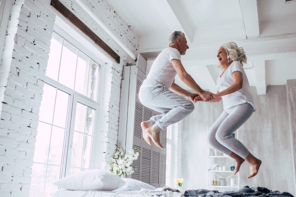Two old couple jumping on the bed