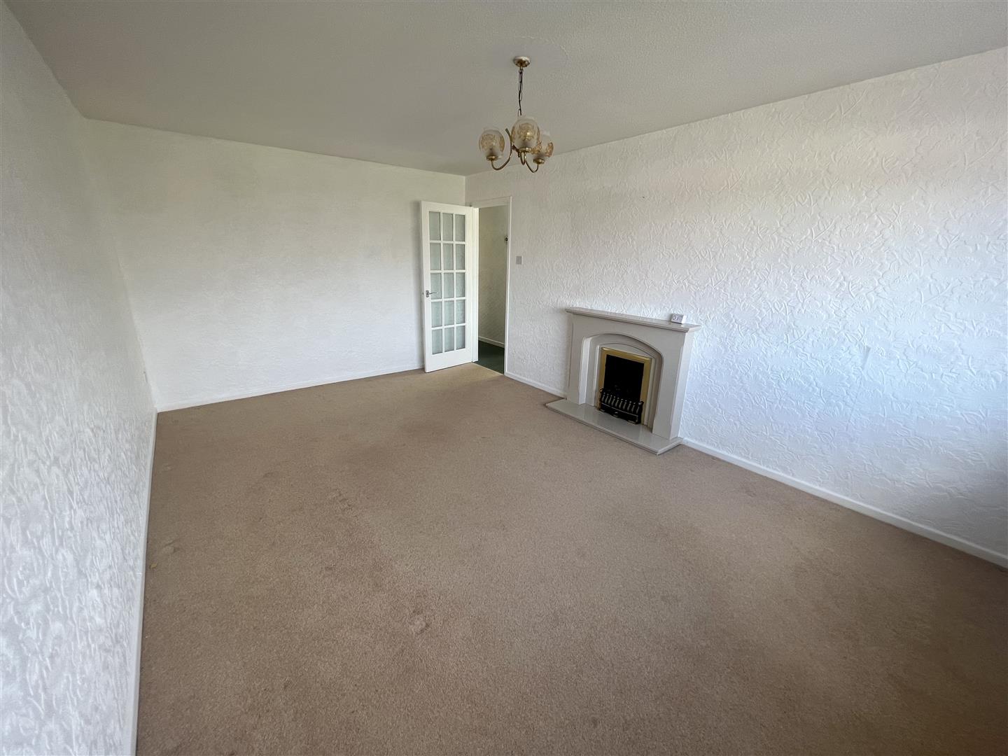 an empty living room with a small fireplace