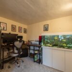 a study room with a big fish pot and a desktop
