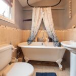 a bathroom with a bath tub, commode and curtains