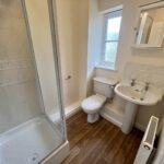 a shower area, sink, and a commode